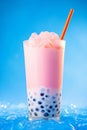 Asian boba tapioca pearls pink bubble tea with cream topping on blue background, vertical photo.