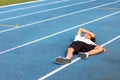 An Asian boy aged 6 to 8 years old is lying on the blue field due to being tired. After jogging in the stadium until exhaustion
