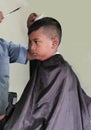 Asian little boy being shaved by barber at the barbershop