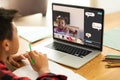 Asian boy with book and pencil looking at laptop screen with african american girl in online class Royalty Free Stock Photo