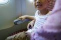 Asian boy child in flight cabin fasten seat belt for safety travel holiday vacation with mother Royalty Free Stock Photo