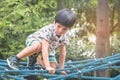 Asian boy climbing on rope bridge in playground Royalty Free Stock Photo