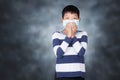 Asian boy Close the nose with mask to aviod PM2.5 on dark mood studio background. Royalty Free Stock Photo