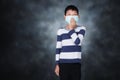 Asian boy Close the nose with mask to aviod PM2.5 on dark mood studio background. Royalty Free Stock Photo