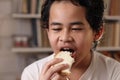 Asian boy eating bread with chocolate cream, student enjoys breakfast or snacks of toast with jam Royalty Free Stock Photo