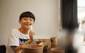 Asian boy eating steak & smiling at camera