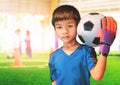 Asian boy football goalkeeper wearing gloves and holding a soccer ball with training ground copy space Royalty Free Stock Photo