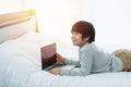 Asian boy in front of laptop computer lay on bed with smile Royalty Free Stock Photo