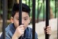 Asian boy Hand in jail looking out the window