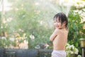 Asian boy has fun playing in water from a hose Royalty Free Stock Photo