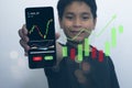 Asian boy holds a smartphone and shows the stock trading screen