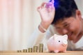 Asian boy inserting a coin in a piggy bank