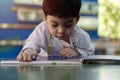 Asian boy laying on the floor and reading a book against multi colored bookshelf in library Royalty Free Stock Photo