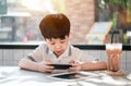 Asian boy learning online in cafe alone. Son relax with play game Royalty Free Stock Photo