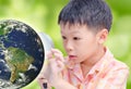 Asian boy looking at glowing globe by magnifying glass Royalty Free Stock Photo