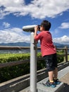 Asian boy looking through telescope with blue sky background Royalty Free Stock Photo