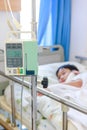 Asian boy lying on sickbed with infusion pump intravenous IV drip. Royalty Free Stock Photo