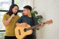 Asian boy playing guitar and mother sing a song and embrace, feel appreciated and encouraged. Concept of a happy family, learning
