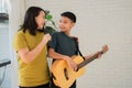 Asian boy playing guitar and mother sing a song and embrace, feel appreciated and encouraged. Concept of a happy family, learning