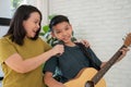 Asian boy playing guitar and mother sing a song and embrace, feel appreciated and encouraged. Concept of a happy family, learning