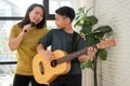 Asian boy playing guitar and mother sing a song and embrace, feel appreciated and encouraged. Concept of a happy family, learning