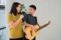 Asian boy playing guitar and mother sing a song and embrace, feel appreciated and encouraged. Concept of a happy family, learning