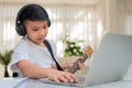 Asian boy playing guitar and watching online course on laptop while practicing for learning music or musical instrument online at Royalty Free Stock Photo