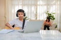 Asian boy playing guitar and watching online course on laptop while practicing for learning music or musical instrument online at Royalty Free Stock Photo