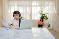 Asian boy playing guitar and watching online course on laptop while practicing for learning music or musical instrument online at Royalty Free Stock Photo