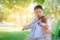 An Asian boy plays the violin in the park. Royalty Free Stock Photo