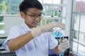 Asian boy pouring blue liquid during learn chemistry at laboratory