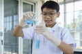 Asian boy pouring blue liquid during learn chemistry at laboratory