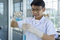 Asian boy pouring blue liquid during learn chemistry at laboratory