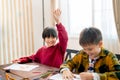 Asian boy raise his hand to ask questing in classroom and his friend look happy during work together