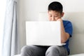 Asian boy sitting on sofa and using laptop Royalty Free Stock Photo