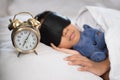 Asian boy sleeping on bed white pillow and sheet with alarm clock and teddy bear Royalty Free Stock Photo