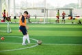 Asian boy soccer player speed run to shoot ball to goal on artificial turf