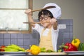 Asian Boy son cooking salad food holdind wooden spoon with vegetable holding tomatoes and carrots, bell peppers on plate for happy Royalty Free Stock Photo