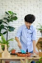 Asian boy spent the holidays taking care of the indoor garden, mixing soil and fertilizer with blue gardening shovel