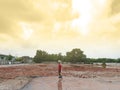 Asian boy stand alone in the demolition wasteland construction area at the sunset time with raylight and cloudy. Royalty Free Stock Photo