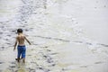 Asian boy takes off his shirt Walking in the mud into the sea at Bangsaen Beach, Chonburi in Thailand. June 21 , 2020