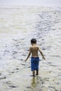 Asian boy takes off his shirt Walking in the mud into the sea at Bangsaen Beach, Chonburi in Thailand. June 21 , 2020