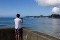 Boy taking picture of the ocean with a mobile device.