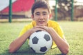Asian boy teenager with a football ball lies on the grass. Sport Royalty Free Stock Photo