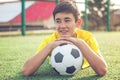 Asian boy teenager with a football ball lies on the grass. Sport Royalty Free Stock Photo