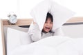 Asian Boy wake up late on seven AM and lazy to go to school. Heis holding a pillow over his ears and crying on white bed in Royalty Free Stock Photo