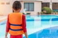 Asian boy wear life jacket near the swimming pool