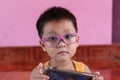 Asian boy wearing glasses and playing on the smart phone Royalty Free Stock Photo
