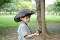 An Asian boy wearing a hat in a forest exploration suit plays with a beetle on his hand