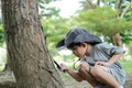 Asian boy wearing a hat in a forest exploration suit Use a magnifying glass to survey the tree area